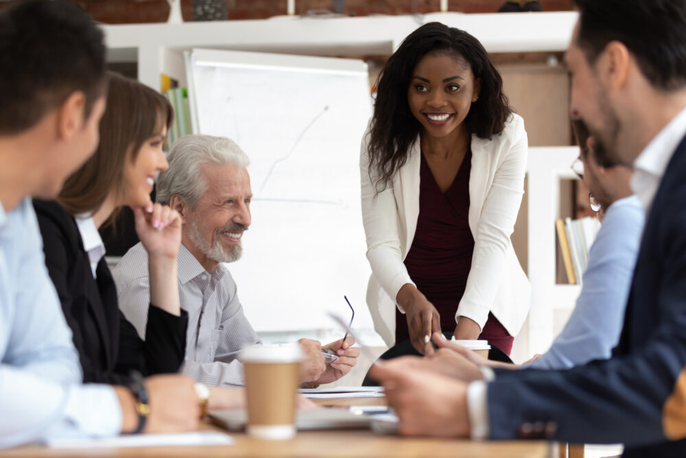 Different ethnicity and age businesspeople gathered together at boardroom for negotiations and planning future collaboration lead by african smiling businesswoman or corporate training process concept